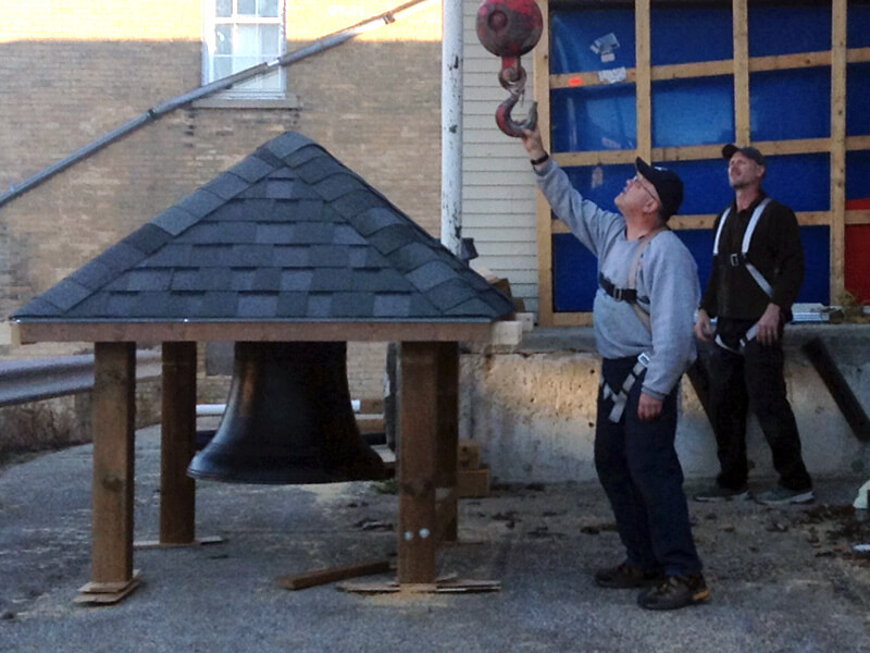 contractors attaching bell to crane at harriston post office